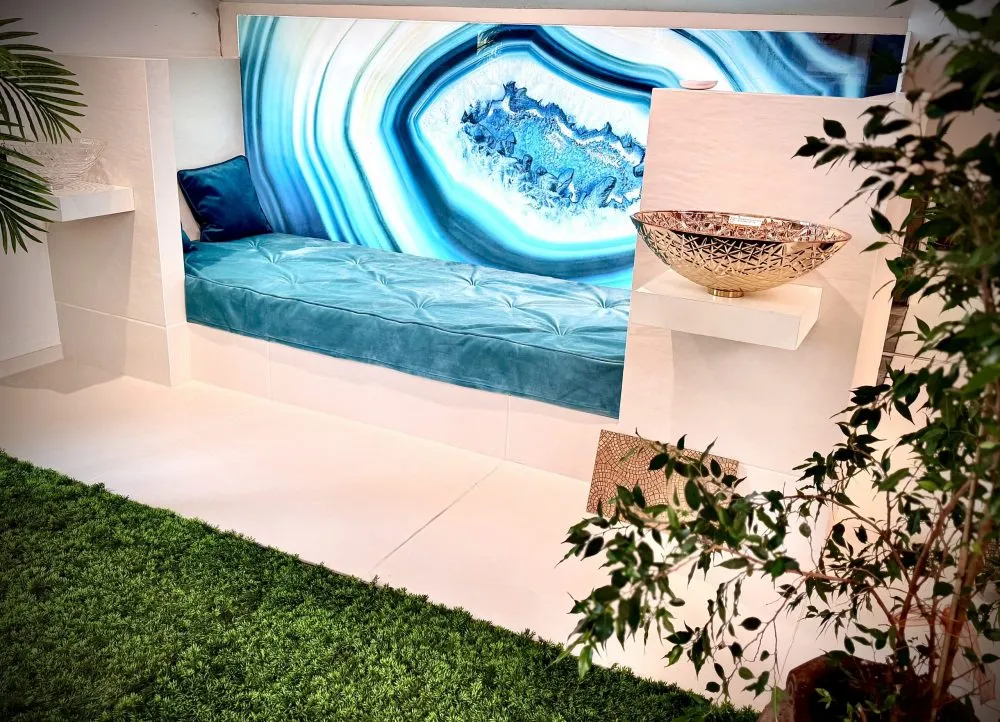 Liege mit Hinterleuchteter Glasplatte mit blausteinoptik. Sehr schön dekoriert mit Pflanzen und Palmen. rechts auf einem Sockel steht ein silberner Waschtisch.