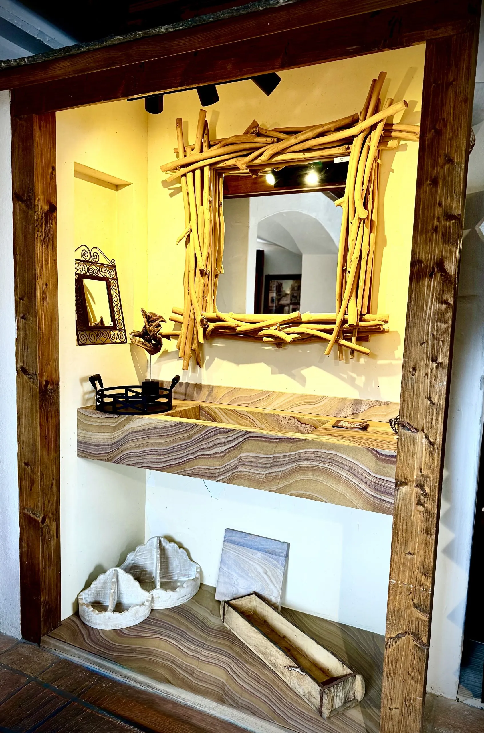 Natursteinwaschtisch Ein Musterwaschtisch aus Naturstein Rainbow. Spiegel mit Rand aus Ästen geflochten.