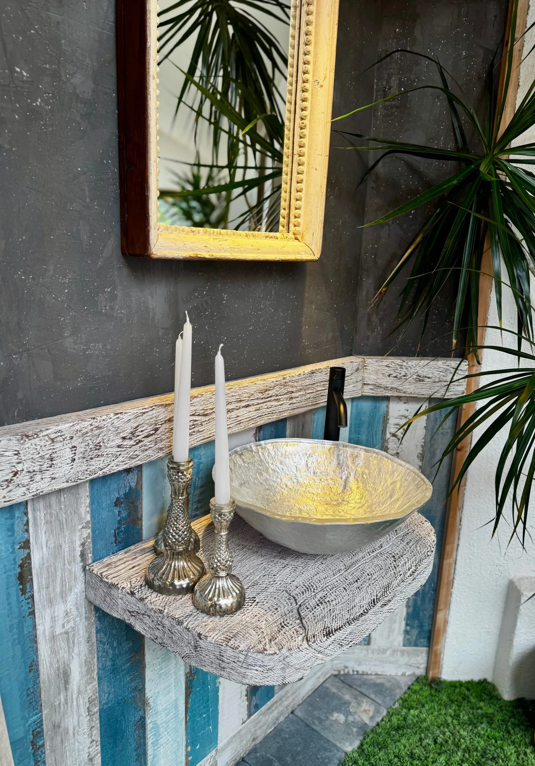 Badezimmermuster mit Silbernen Glaswaschtisch auf einem an der Wandmontierten Holzbrett. Die Rückwand ist gefliest in Holzoptik in verschiedenen blautönen.